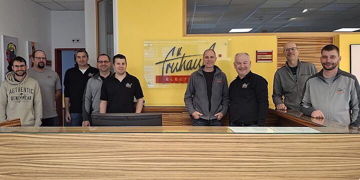 Gruppenfoto Firma Frühauf. Neun freundlch lächelnde Herren