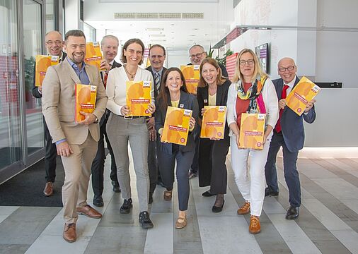 Gruppenfoto: Mitarbeiter:innen halten das Kursprogramm in den Händen