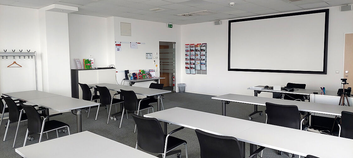 Beispiel Seminarraum in Leonding<br /> Seminarraum. Einige Tische und Stühle und eine Leinwand.