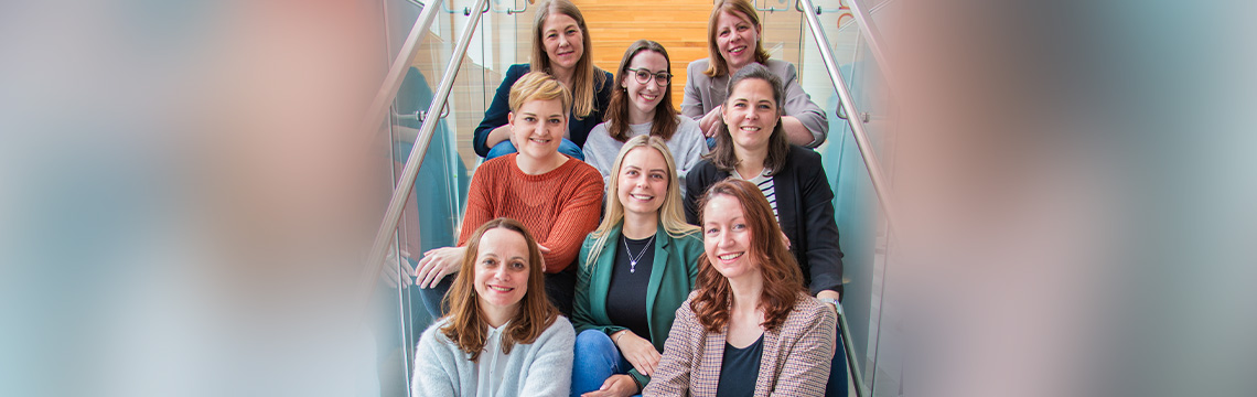 Gruppenfoto des Teams "Firmeninterne Trainings". Acht freundlich lächelnde Damen.